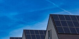 Moderne Wohnhäuser mit Photovoltaik-Anlagen auf den Dächern unter blauem Himmel
