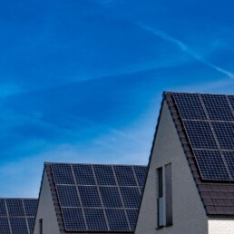Moderne Wohnhäuser mit Photovoltaik-Anlagen auf den Dächern unter blauem Himmel